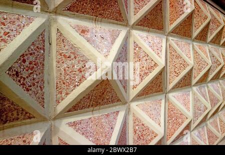 Diminishing perspective of a 3D geometric patterned concrete with red stones wall Stock Photo