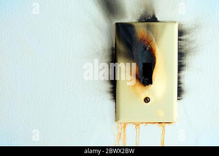 Burned Electrical Switch with White Concrete Wall Texture Background. Stock Photo