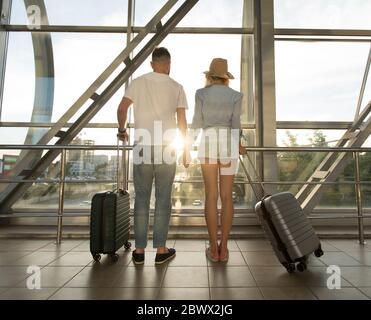 Back view of couple standing in airport with luggage Stock Photo