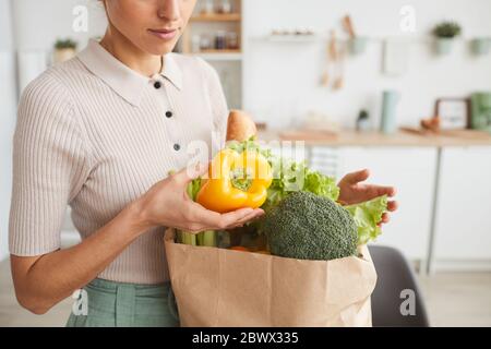 Close-up of woman taking out the fresh vegetables from the paper bag at home Stock Photo