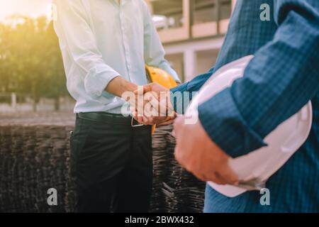 Closeup hand Engineer shake hands agree success project at construction work place Stock Photo
