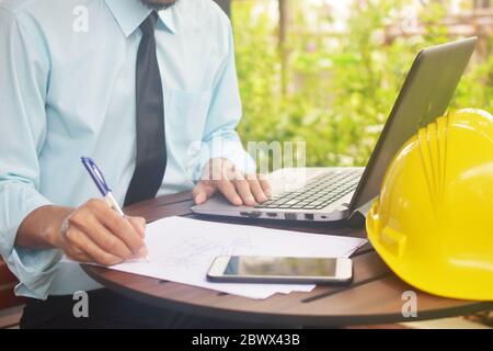 Construction engineers are working to design the building structure with a computer on a wooden work desk Stock Photo