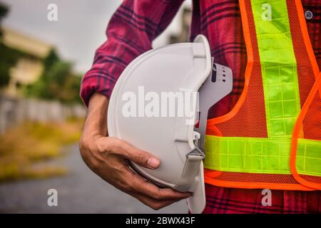 Close up engineering holding white safety hard hat  standing out doors Stock Photo