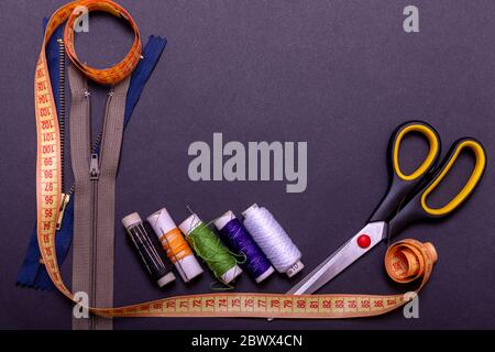 Copyspace frame with sewing tools and accesories. Tools for sewing and handmade: thread, scissors, pins on black paper. Stock Photo