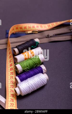 Copyspace frame with sewing tools and accesories. Tools for sewing and handmade: thread, scissors, pins on black paper. Stock Photo