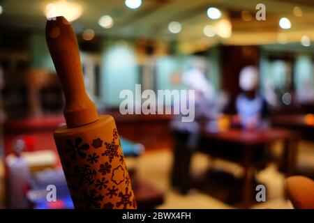 Close up Baking Rolling Pin with Blurred Chefs Making Cookies for Christmas Time. Stock Photo