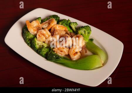 Plate of prawns with broccoli and acorn ham on wooden table Stock Photo