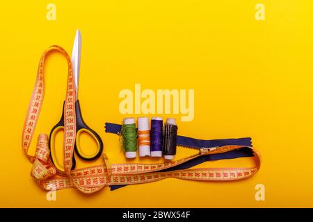 Flat lay of colored thread rolls and Scissors for sewing yellow background. Sewing and needlework concept. Tools for sewing and handmade: thread, scis Stock Photo