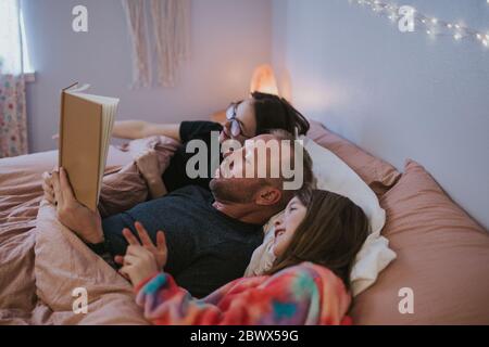 portrait of father reading to daughters Stock Photo