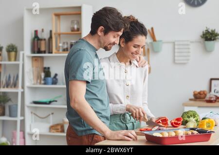 Young couple preparing food together in the kitchen they preparing dish from vegetables Stock Photo