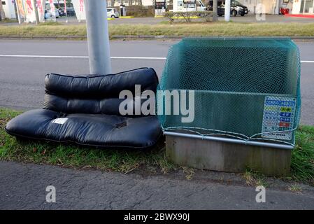 TOMAKOMAI, JAPAN - NOVEMBER 16, 2019: Discarded sofa left beside the garbage bin on footpath. In Japan garbage be collected on designated days, follow Stock Photo