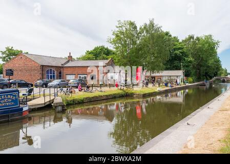 Visitors to Fradley Canalside Cafe at Fradley Junction in Staffordshire sit on the grass verge eating and drinking Stock Photo