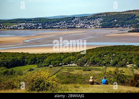 People sitting admiring Ariel view from Arnside Knot Cumbria of Grange over Sands across  the Kent estuary at the seaside  resort of Arnside Stock Photo