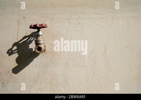 Old Tap on Raw Concrete Wall with Shadow, Suitable for Minimal Concept. Stock Photo