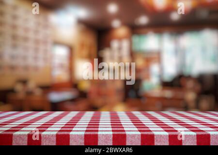 Empty Table Covered with Red Checkered Tablecloth and Blurred Restaurant Background. Stock Photo
