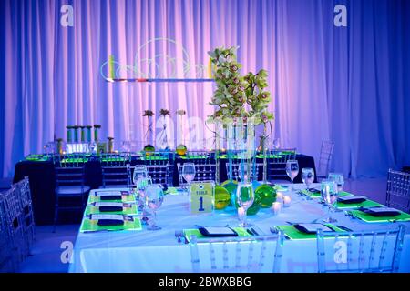 Fancy guest table set up for a wedding or social event in the ballroom orchid and lucite center piece green and red Stock Photo
