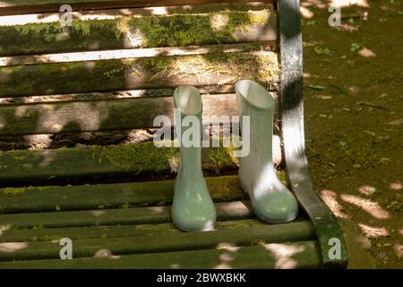a close up view of a pair of kids boots that have been left on a park bench in a public forest Stock Photo
