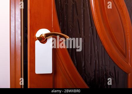 Do not disturb sign at the door. Empty label or flyer on a door handle for your text. Stock Photo