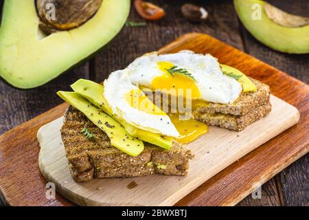 avocado sliced ​​on toasted bread with spices, Avocado sandwich with fried vegetarian egg. Stock Photo