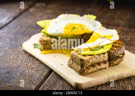 healthy breakfast, gluten-free bread, with slices of avocado cut on whole toast and fried egg. Stock Photo