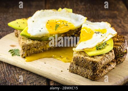 healthy breakfast, gluten-free bread, with slices of avocado cut on whole toast and fried egg. Stock Photo