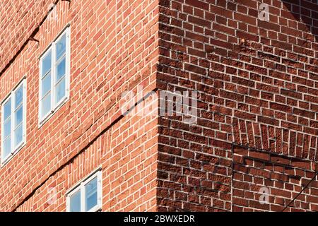 Corner of a house made of red bricks with one wall in sunshine and the other in shadow, abstract Stock Photo