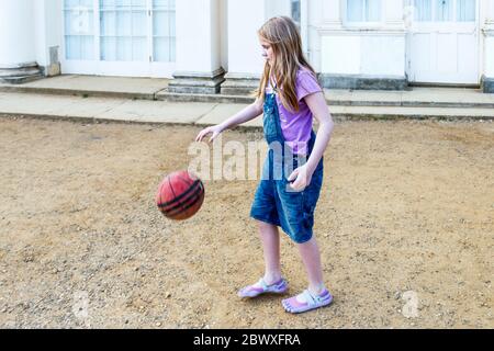 An eleven year-old girl bouncing a basketball in the park, London, UK Stock Photo