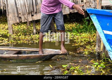 Africa, West Africa, Benin, Lake Nokoue, Ganvié. A young man is walking on a pirogue. Stock Photo