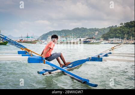 Boat captains and their help set up the long tail boats that take the tourists out to the lagoons, beaches and Islands around El Nido, Palawan, The Ph Stock Photo