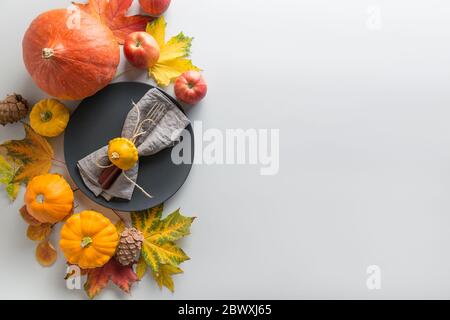 Fall table setting as frame with cutlery, plate, pumpkins, leaves, apples on grey. View from above. Horizontal orientation. Space for text Stock Photo