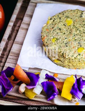 raw vegan burger, before being fried. Thawed meat, with lots of vegetables around. Tomato, sliced ​​onion, peppers, red cabbage. Stock Photo