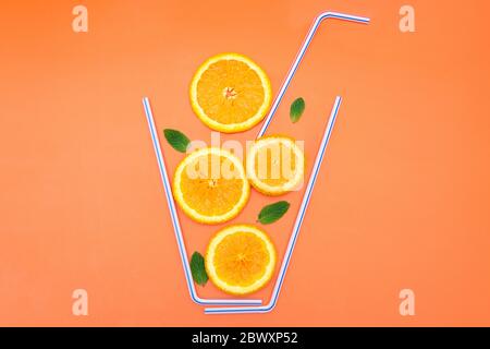 Creative flat lay composition made of orange slices, fresh mint leaves and cocktail straws on a bright orange background. Refreshing and juicy summer Stock Photo