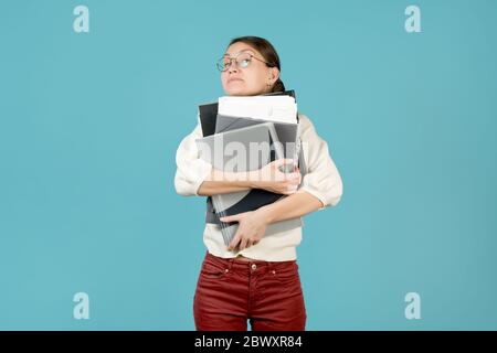 Girl hugs a large stack of documents and folders. Overloaded office employee Stock Photo