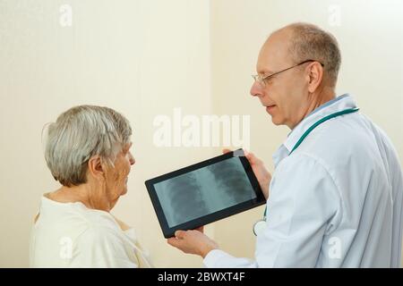 Doctor shows the results of an examination of the lungs of an elderly woman on the screen of a tablet Stock Photo