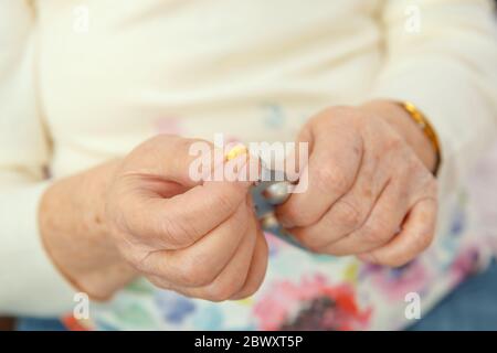 An elderly woman is going to swallow a medicine, a pill and drink it with water. Closeup of a hand with a tablet. Stock Photo