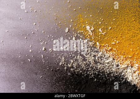 Colorful explosion of three ingredients: activated carbon, coconut and turmeric on grey background Stock Photo