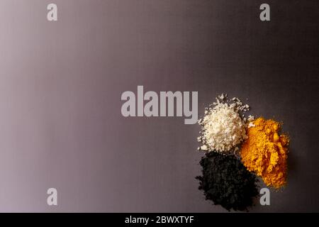 Violet background with colorful explosion of ingredients - activated carbon, coconut and turmeric Stock Photo