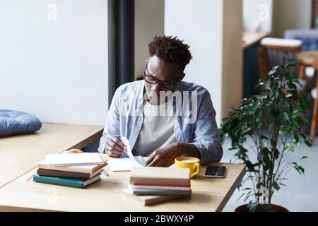 Hardworking African American student working on research in university canteen Stock Photo
