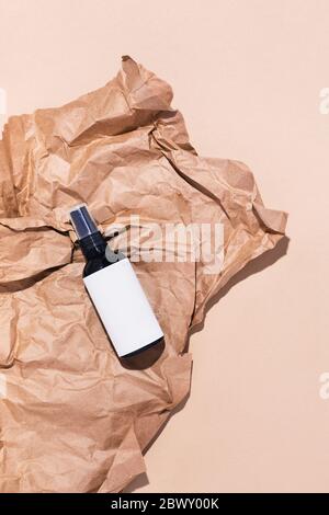 A spray bottle with facial tonic, mycelar water or body lotion located on crumped paper. Picture In soft colors. Stock Photo