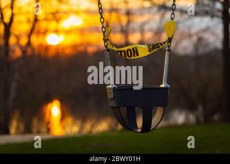 A swing wrapped in caution tape at a local park during the Illinois Stay At Home order due to COVID-19 Coronavirus pandemic. Stock Photo