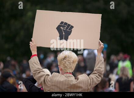 Blond haired man holding up a homemade black fist sign, at  the Black Lives Matter UK protest march. London, England, UK Stock Photo