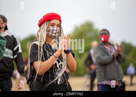 Young woman, wearing a red beret and face mask, clapping during the Black Lives Matter UK protest march. London, England, UK Stock Photo