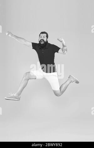 Healthy guy feeling good. Inspired concept. Towards fun. Enjoying active lifestyle. Happy guy jumping. Active bearded man in motion yellow background. Active and energetic hipster. Energy charge. Stock Photo
