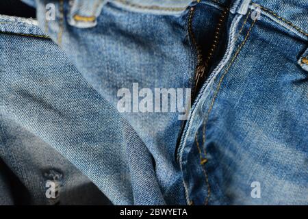 Zipper of ripped denim pants. Textile, denim background. Fashion, tailoring, clothing repair concept. Stock Photo