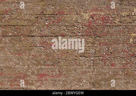 Old Raw grunge rough bumpy concrete texture with remaining scratch of red painted and corrosive surface. Texture of exterior old bunker. Stock Photo
