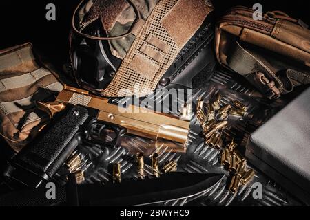 Photo of a tactical helmet, bullet shells, knife and desert eagle gun laying on metal surface. Stock Photo