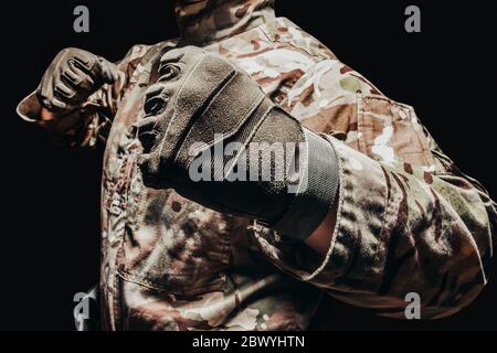 Photo of a soldier in multicam camouflage tunic in punching pose on black background. Stock Photo