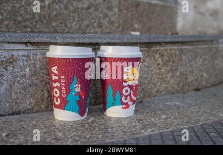 Two used disposable Costa Coffee cups with a Christmas themed design left on a set of outside stairs. London Stock Photo