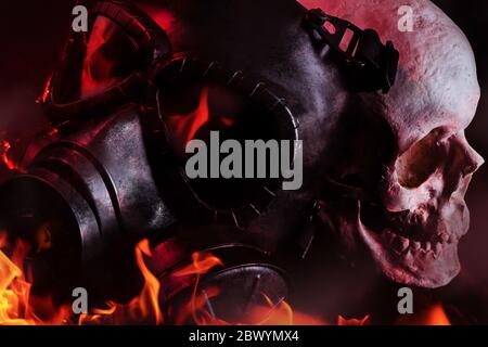 Photo of a black burning military gas mask laying in flames with human skull on black background. Stock Photo