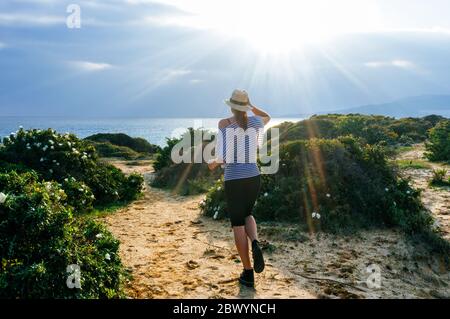 Beautiful young woman strolling along the coast at sunset. Beautiful day on field. Young woman enjoying nature. Spring freedom enjoy concept. Stock Photo